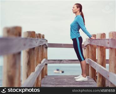 Sporty young woman stretching next to the sea coast