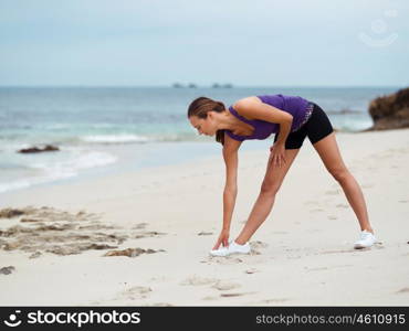 Sporty young woman stretching on the sea coast