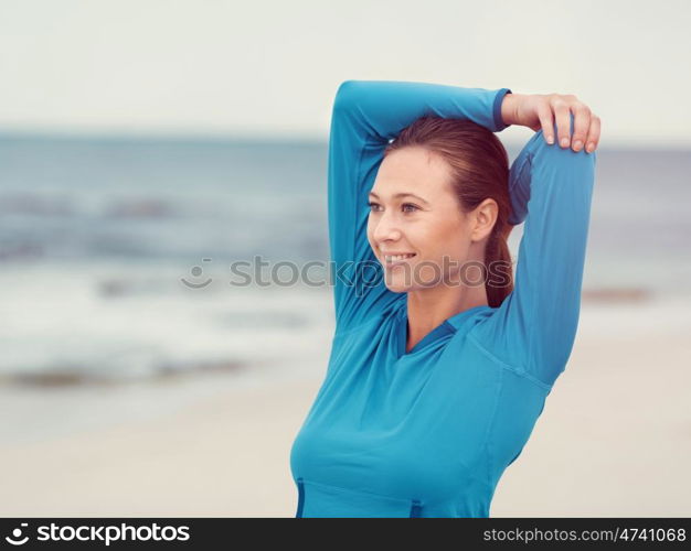 Sporty young woman stretching on the sea coast