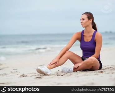 Sporty young woman stretching on the sea coast