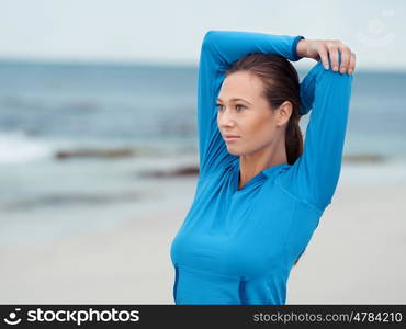 Sporty young woman stretching on the sea coast