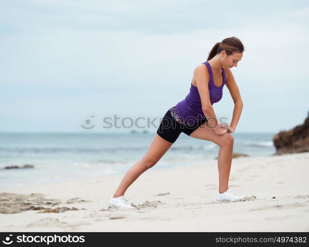 Sporty young woman stretching on the sea coast