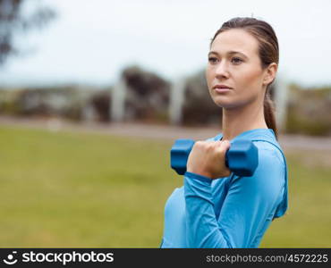 Sporty young woman with dumbbells outdoors