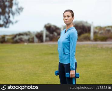 Sporty young woman with dumbbells outdoors