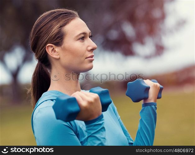 Sporty young woman with dumbbells outdoors