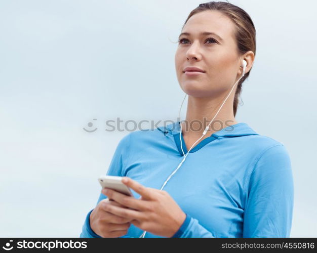 Sporty young woman with earphones on the sea coast