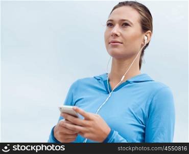 Sporty young woman with earphones on the sea coast