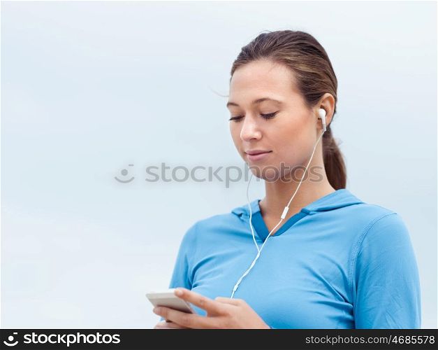 Sporty young woman with earphones on the sea coast