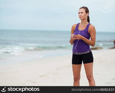 Sporty young woman with earphones on the sea coast