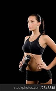 Sporty young woman with headphones and bottle on black background