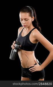 Sporty young woman with headphones and bottle on black background