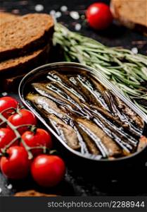 Sprats with cherry tomatoes on the table. Against a dark background. High quality photo. Sprats with cherry tomatoes on the table.