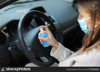 Spraying anti-bacterial sanitizer spray on hand in car, infection control concept. Sanitizer to prevent Coronavirus, Covid-19, flu. Spray bottle. womanwearing in medical protective mask driving a car. Spraying anti-bacterial sanitizer spray on hand in car, infection control concept. Sanitizer to prevent Coronavirus, Covid-19, flu. Spray bottle. womanwearing in medical protective mask driving a car.