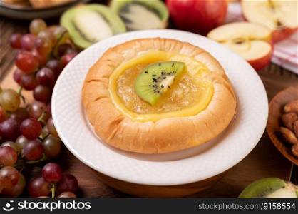 Spread the bread with jam and place it with kiwi and grapes. The apple on the wooden table