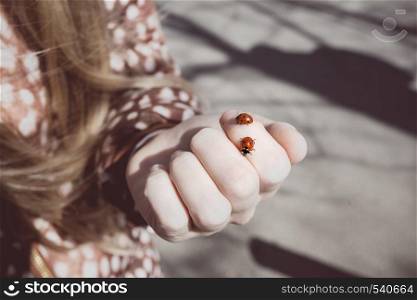 spring - a little girl holds in the palm of ladybirds