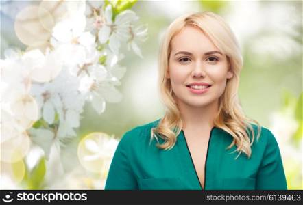 spring and people concept - smiling young woman face over natural cherry blossom background. smiling young woman portrait