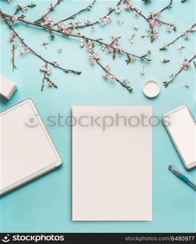 Spring background with cherry blossom twigs on blue desktop, top view, frame