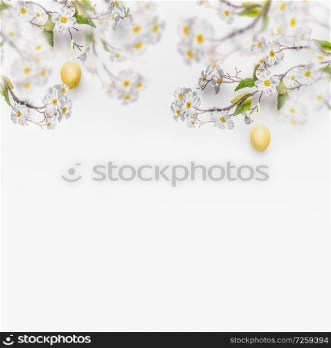 Spring blossom branches with hanging yellow Easter eggs at white wall background, banner. Fresh modern decorative concept. Easter background with copy space