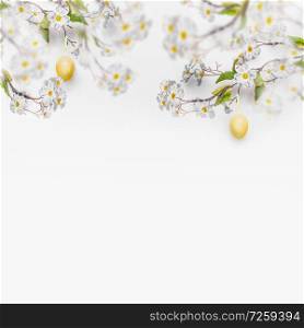 Spring blossom branches with hanging yellow Easter eggs at white wall background, banner. Fresh modern decorative concept. Easter background with copy space