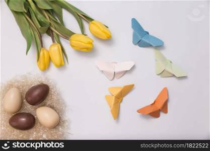 spring composition with chocolate eggs tulips paper butterflies