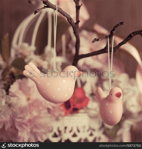 Spring decor - pink birds on the branch in shabby chic cage with flowers. The spring decor