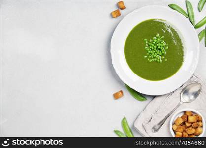 Spring detox pea green cream soup over light grey marble background, top view. Clean eating, dieting, vegan, vegetarian, healthy food concept