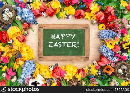 Spring flowers and easter eggs. Tulips, narcissus, hyacinth. Chalkboard with sample text Happy Easter!