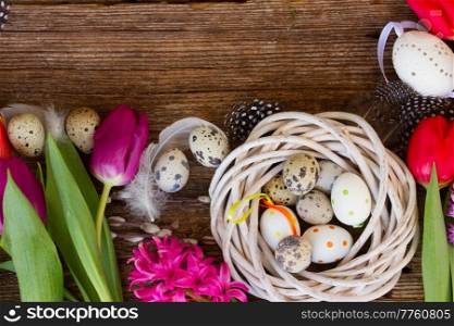 Spring fresh tulips with easter eggs  in nest on wooden table with copy space. Spring flowers with easter eggs