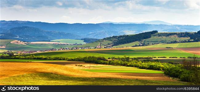 Spring green field and meadows on the hills panorama. Picturesque valley in Tatras mountains of Slovakia. Rural scene. Village and countryside landscape.