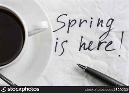 Spring is coming. Spring is here message written on napkin and cup of coffee