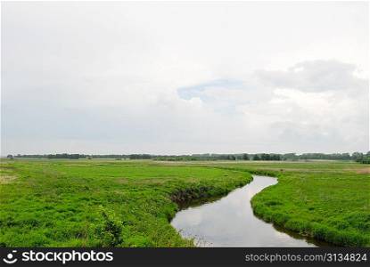 spring meadow, river and sky with clouds