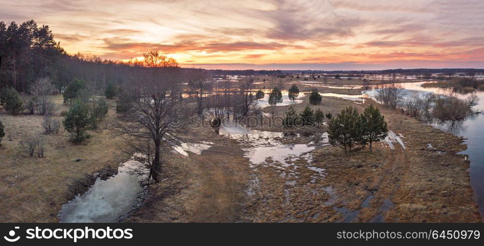 Spring melting river flood panorama. Sunset over thaw meadows. Streaming water at early springtime. Drone view
