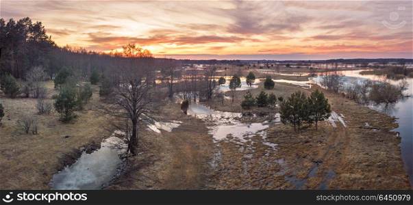 Spring melting river flood panorama. Sunset over thaw meadows. Streaming water at early springtime. Drone view