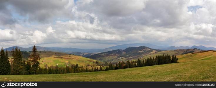 Spring mountain panorama. Clouds and sun on the hills. Spring storm. April rain. Village in the valley. April rural scene