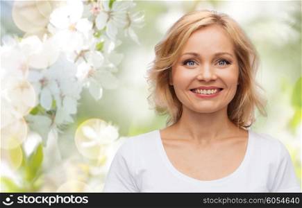 spring, nature and people concept - smiling woman in blank white t-shirt over cherry blossom background