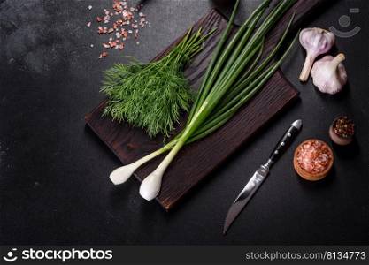 Spring onions, dill, garlic and hot pepper as well as spices and herbs on a wooden cutting board as ingredients in the preparation of traditional Ukrainian borscht. Spring onions, dill, garlic and hot pepper as well as spices and herbs
