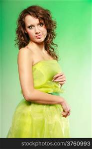 Spring or summer concept. Portrait of curly girl young woman in green dress on green. Studio shot.