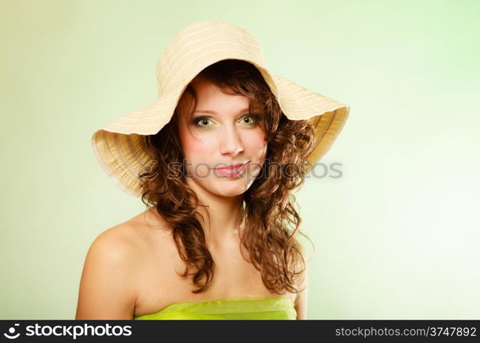 Spring or summer concept. Portrait of curly girl young woman in hat and green dress on green. Studio shot.