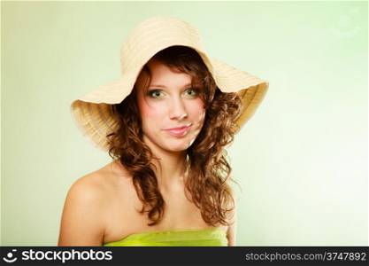 Spring or summer concept. Portrait of curly girl young woman in hat and green dress on green. Studio shot.