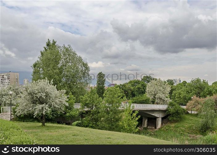 Spring panorama of a part of residential district neighborhood along a lake with green trees, flowering willow, shrubs and flowers, Drujba, Sofia, Bulgaria
