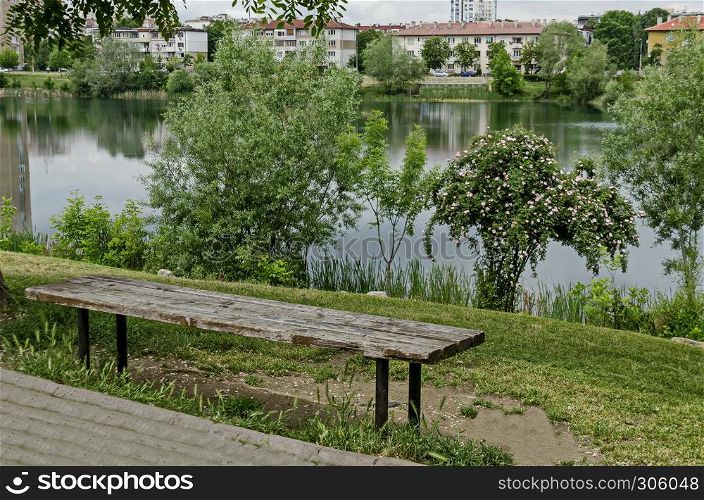 Spring panorama of a part of residential district neighborhood along a lake with green trees, shrubs and flowers, Drujba, Sofia, Bulgaria