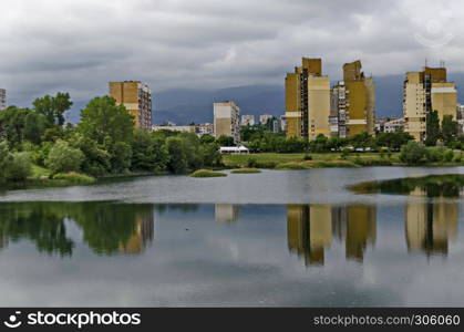 Spring panorama of a part of residential district neighborhood along a lake with green trees, shrubs and flowers, Drujba, Sofia, Bulgaria