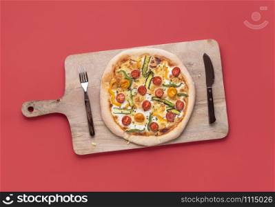 Spring pizza on wooden cutting board and red background. Above view of pizza primavera, homemade. Vegetarian pizza. Italian cuisine. Healthy pizza.