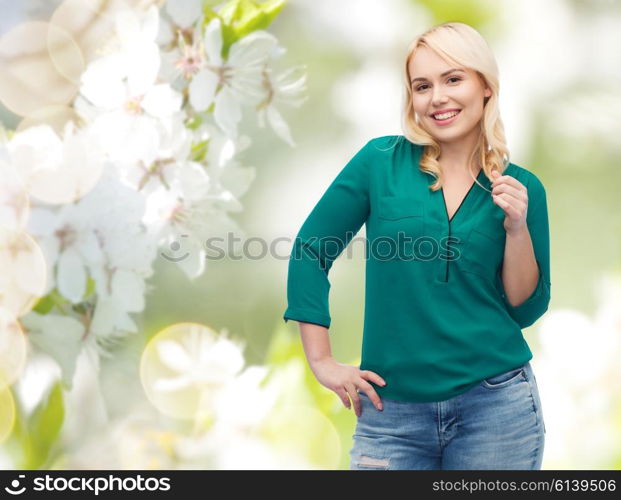 spring, plus size and people concept - smiling young woman in shirt and jeans over natural cherry blossom background