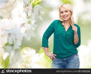 spring, plus size and people concept - smiling young woman in shirt and jeans over natural cherry blossom background