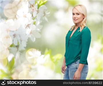 spring, plus size and people concept - smiling young woman in shirt and jeans over natural cherry blossom background