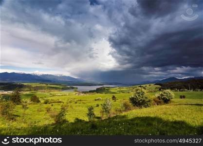 Spring rain and storm in mountains. Green spring hills of Slovakia. Spring stormy scene. Clouds and sunny countryside.