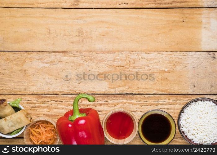 spring roll red bell pepper sauces rice bowl wooden desk