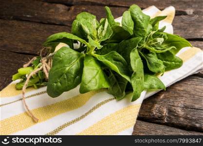 Spring spinach leaves on dark wooden background with kitchen cloth