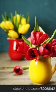 Spring tulips in vases on wooden table - spring, easter or gardening concept